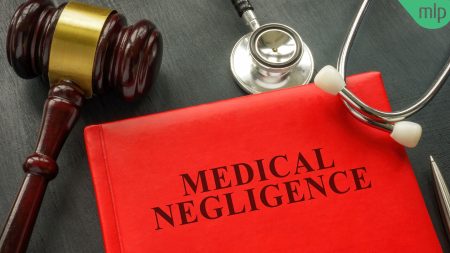 Red book with the title "Medical Negligence" in black text, with a Gavel and Stethoscope lying on either side of it on a black surface