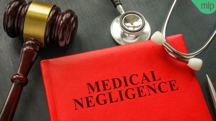 Red book with the title "Medical Negligence" in black text, with a Gavel and Stethoscope lying on either side of it on a black surface