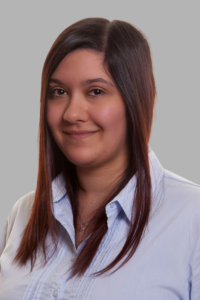 A head shot of a smiling woman with red hair facing the camera. She is wearing a blue shirt