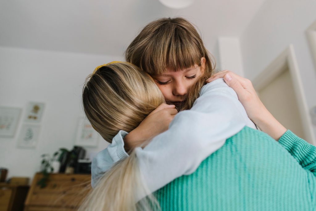 A mother and daughter hugging each other in their home