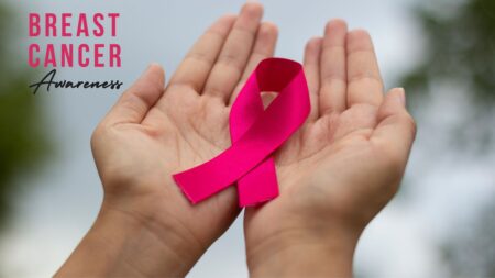 A person holding out a pink ribbon in their palms, with the Breast Cancer Awareness logo in the top left corner