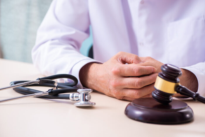 Medical negligence legal consultation, a doctor sat across a table with a stethoscope and a gavel in front of him