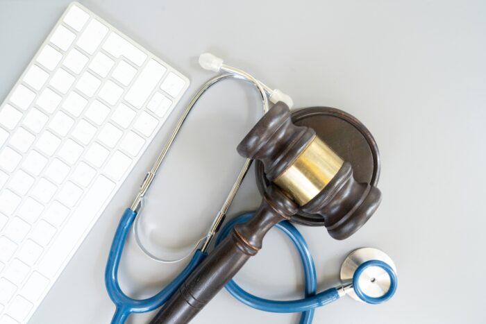 Law Gavel on a table alongside a stethoscope and keyboard.