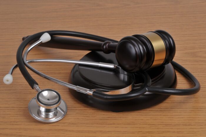 Gavel and stethoscope on top of a light brown table