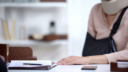 A person with an injured arm reaching across the table for a set of documents
